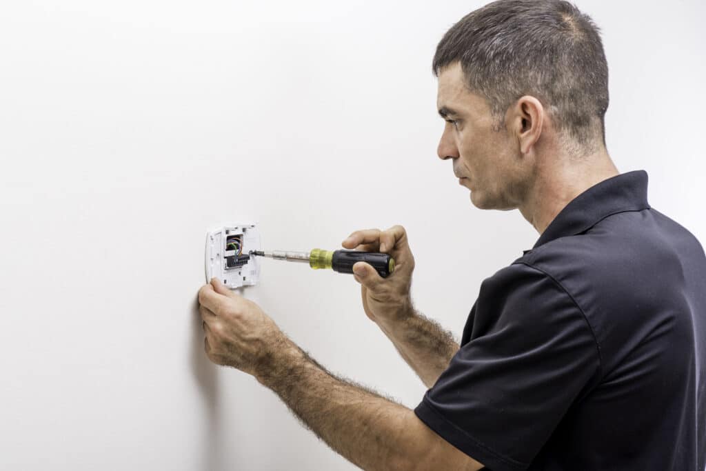 HVAC Efficiency: An HVAC technician installing a thermostat.