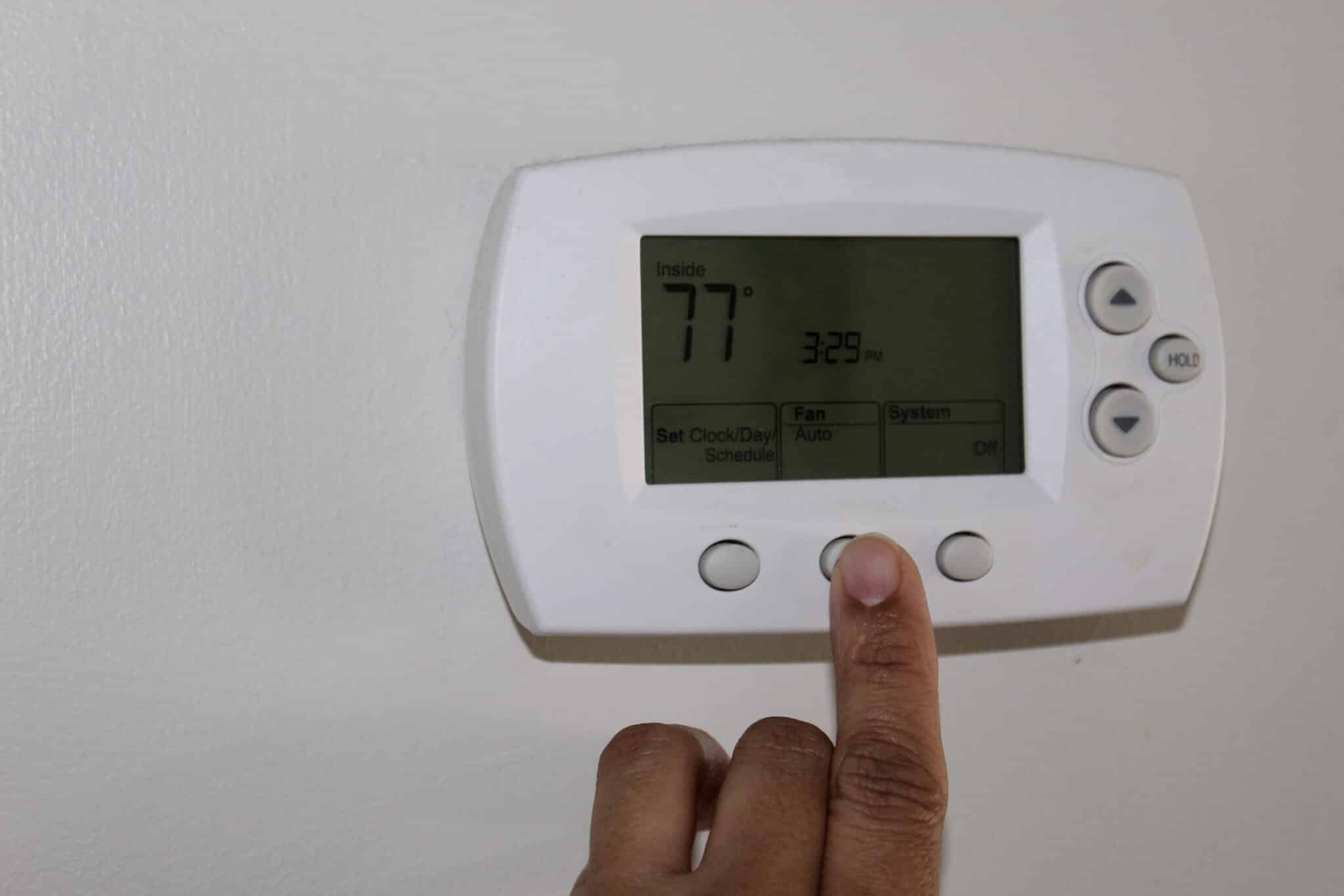 A woman adjusting a thermostat, Optimal HVAC Performance.