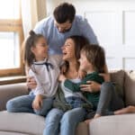 Happy young family with kids relaxing at home, enjoying comfort with their HVAC system.