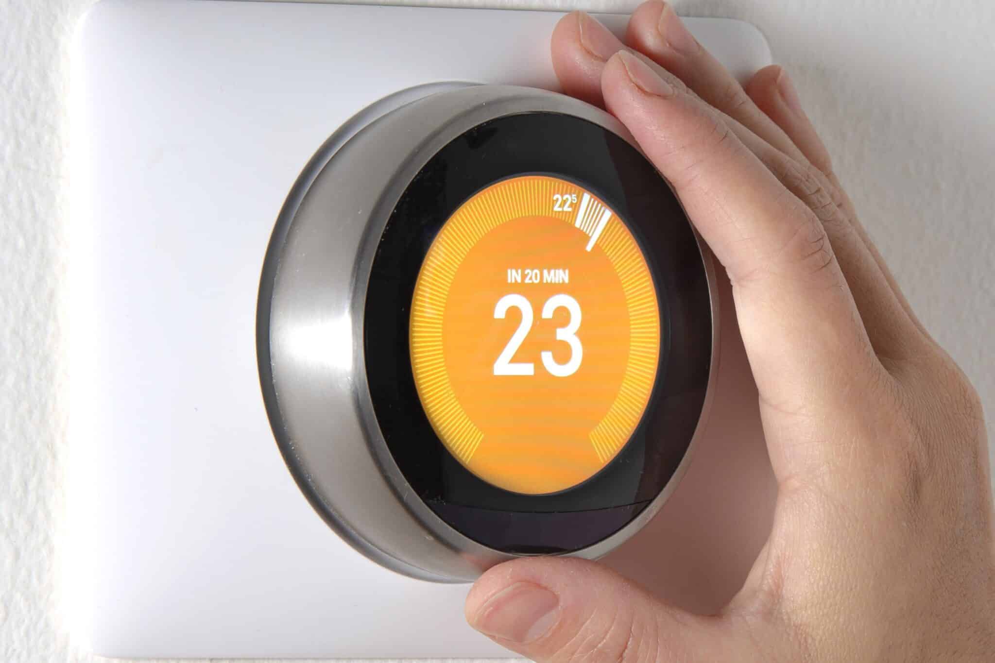 Smart Thermostat with a hand setting up the temperature, HVAC Solutions.