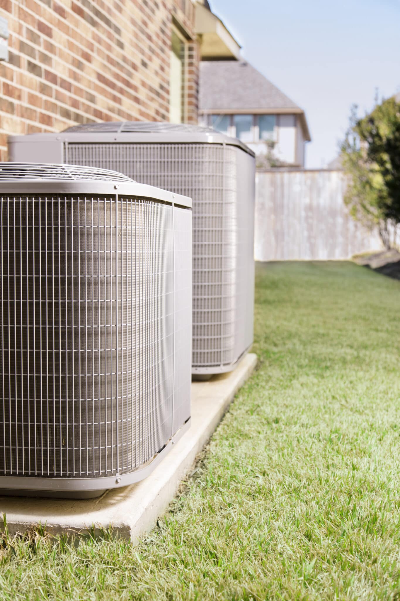 Two air conditioner units outside a large brick home, HVAC Zoning.